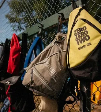 Paddle bags and jackets hung along the chain-link fence at the courts