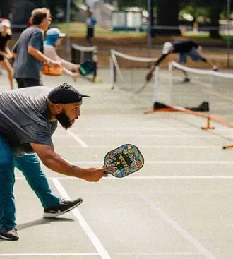 A player stretching low for a shot during open play, with more games running on the courts behind